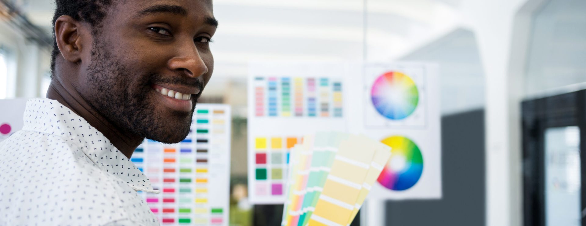 Male graphic designer holding color swatch in office